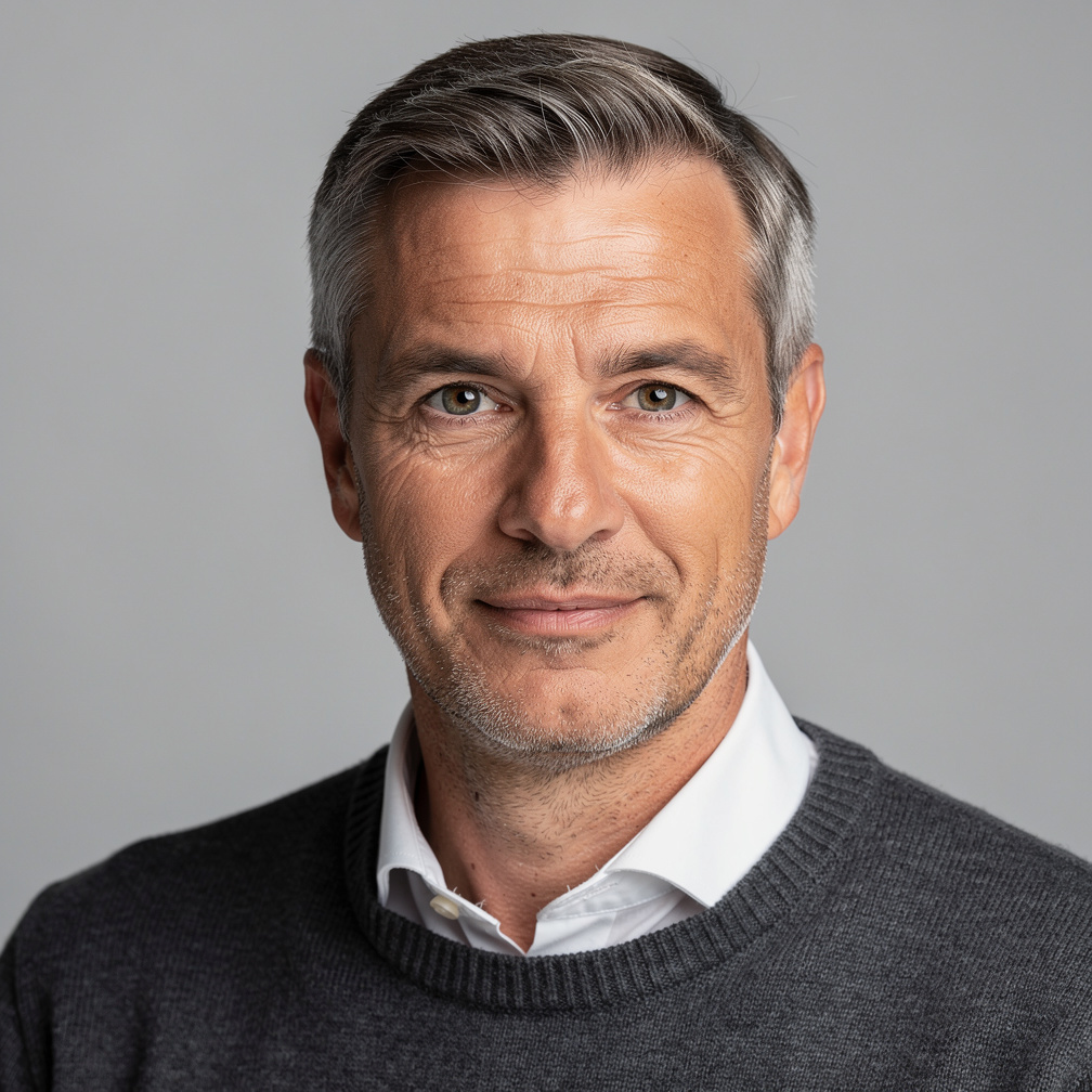 Studio portrait of an older man with gray hair and a sweater