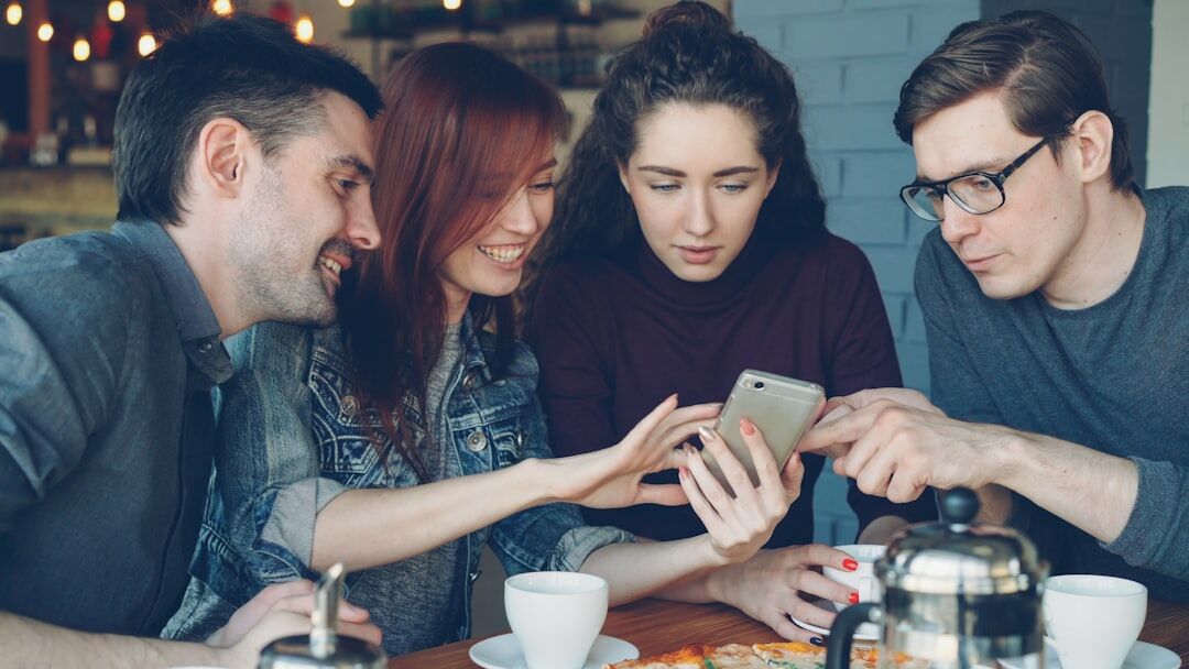 Group of young adults looking at their phones together